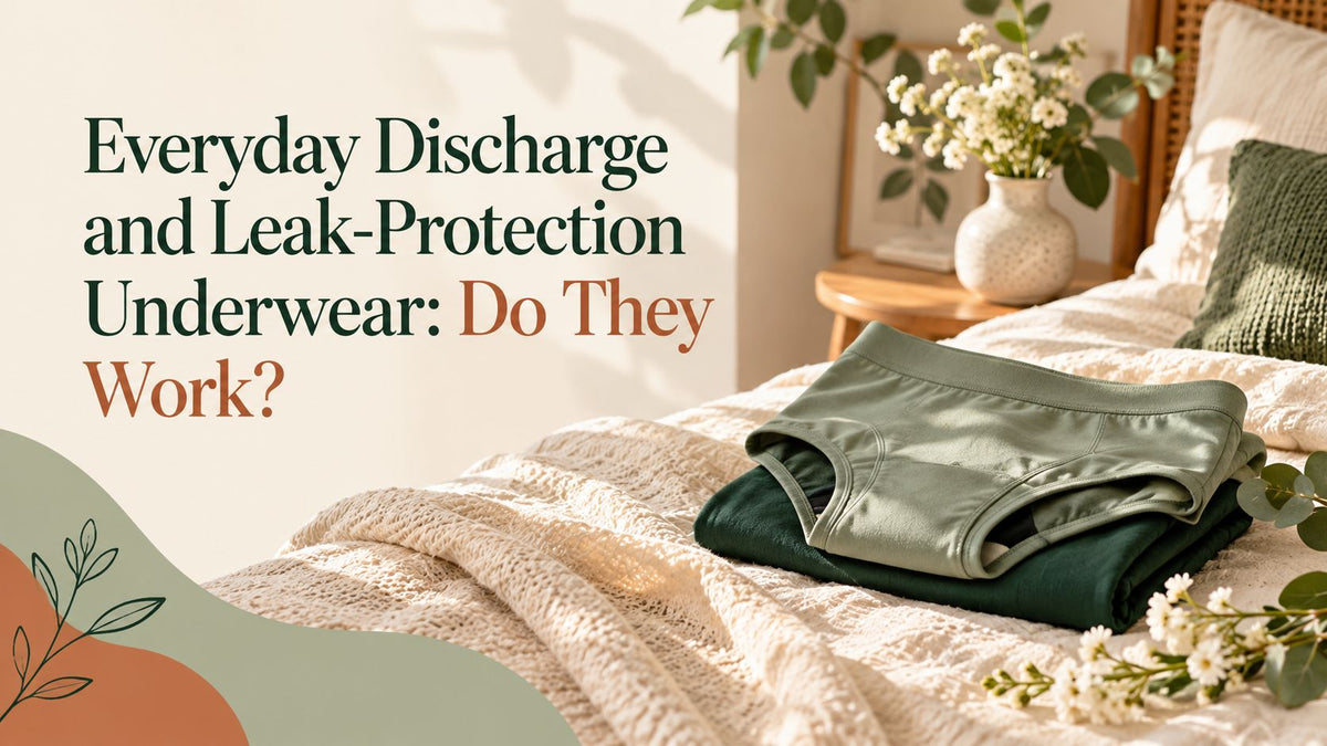 Folded sage and dark green underwear on a cream bedspread beside a vase of white flowers