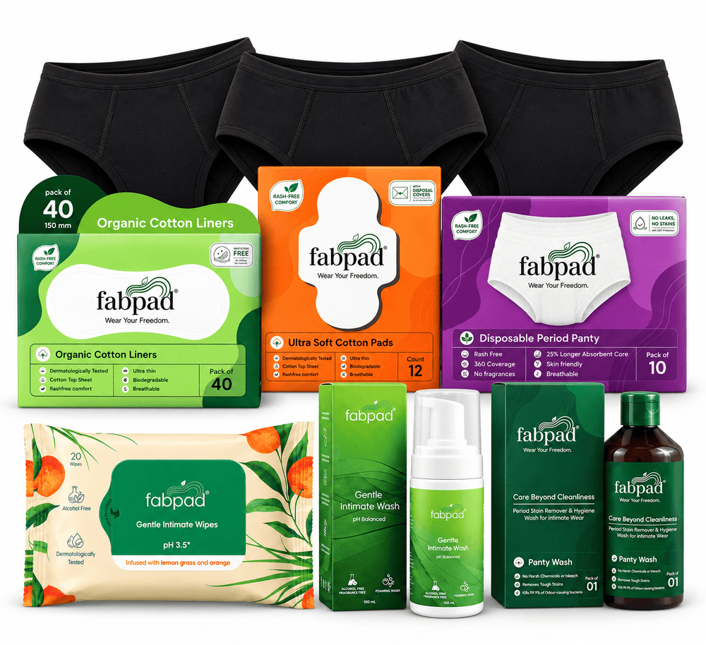 A Fabpad menstrual care bundle featuring black underwear, boxes of cotton liners and period panties, a box of intimate wipes, a green intimate wash bottle, a green cleansing foam bottle, and a brown body wash bottle, all arranged on a white background.